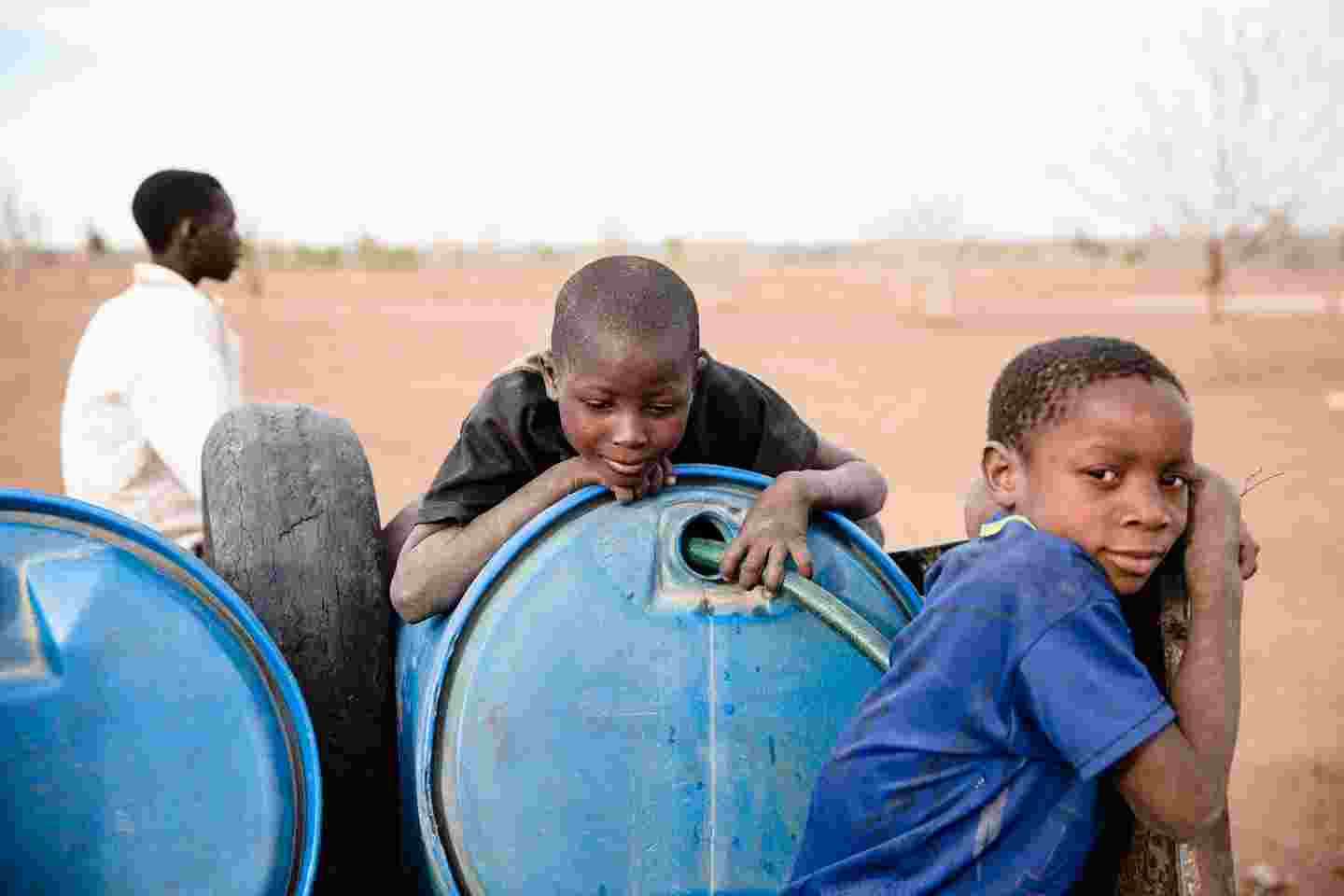 Zimbabwean boys by a water barrel.