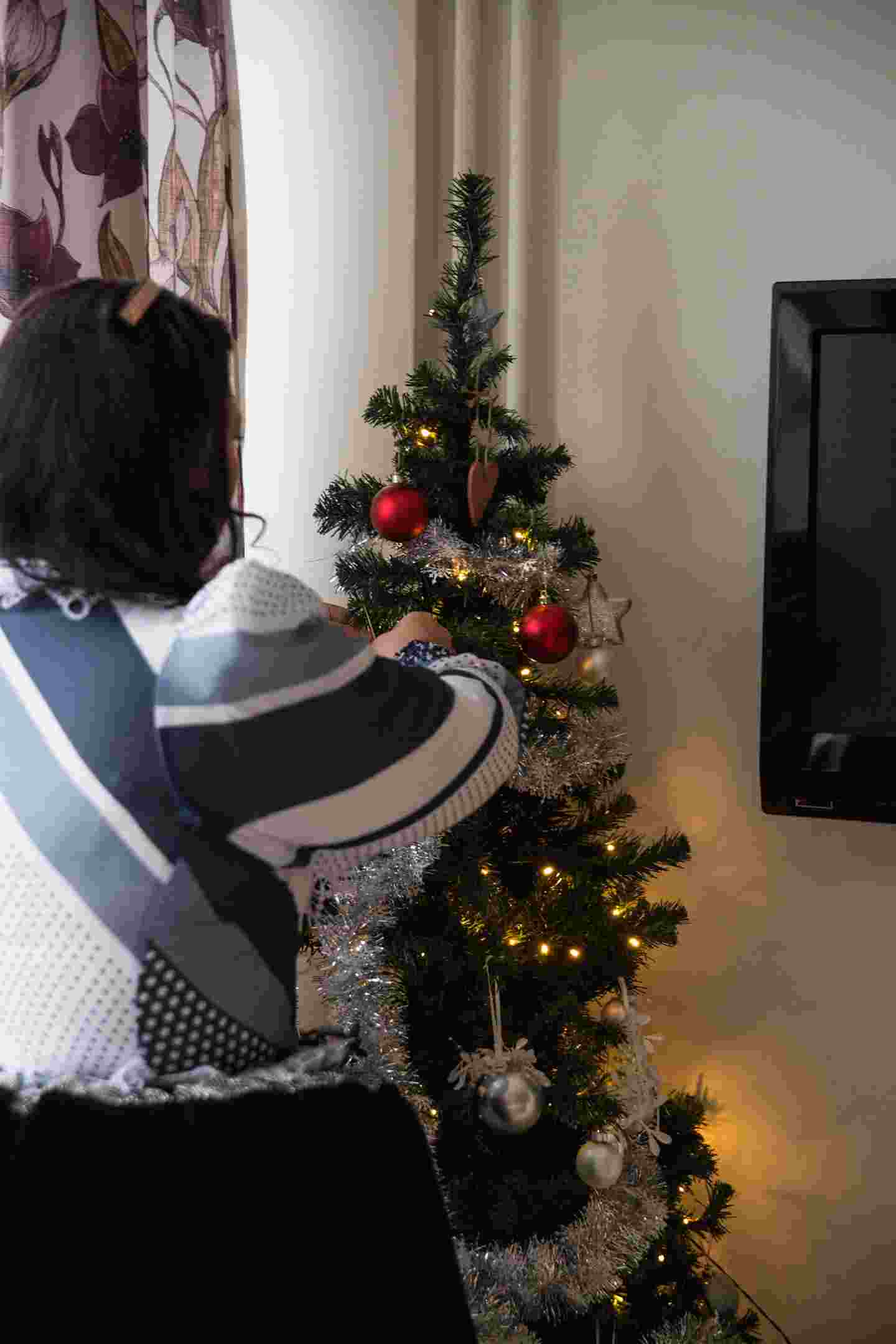 A person decorating a Christmas tree.