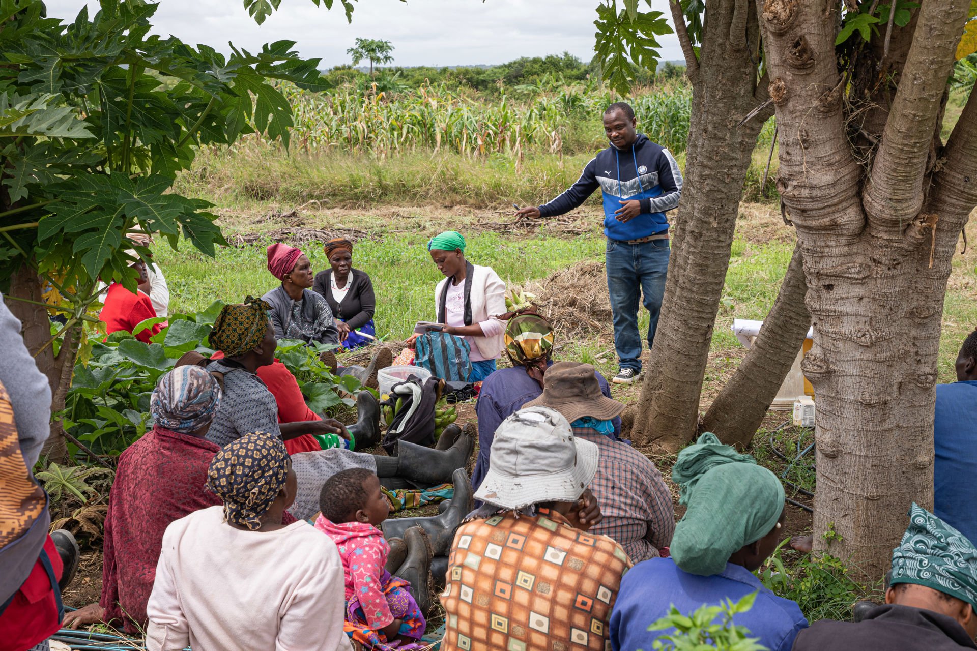 A man talking to people sitting on the ground.