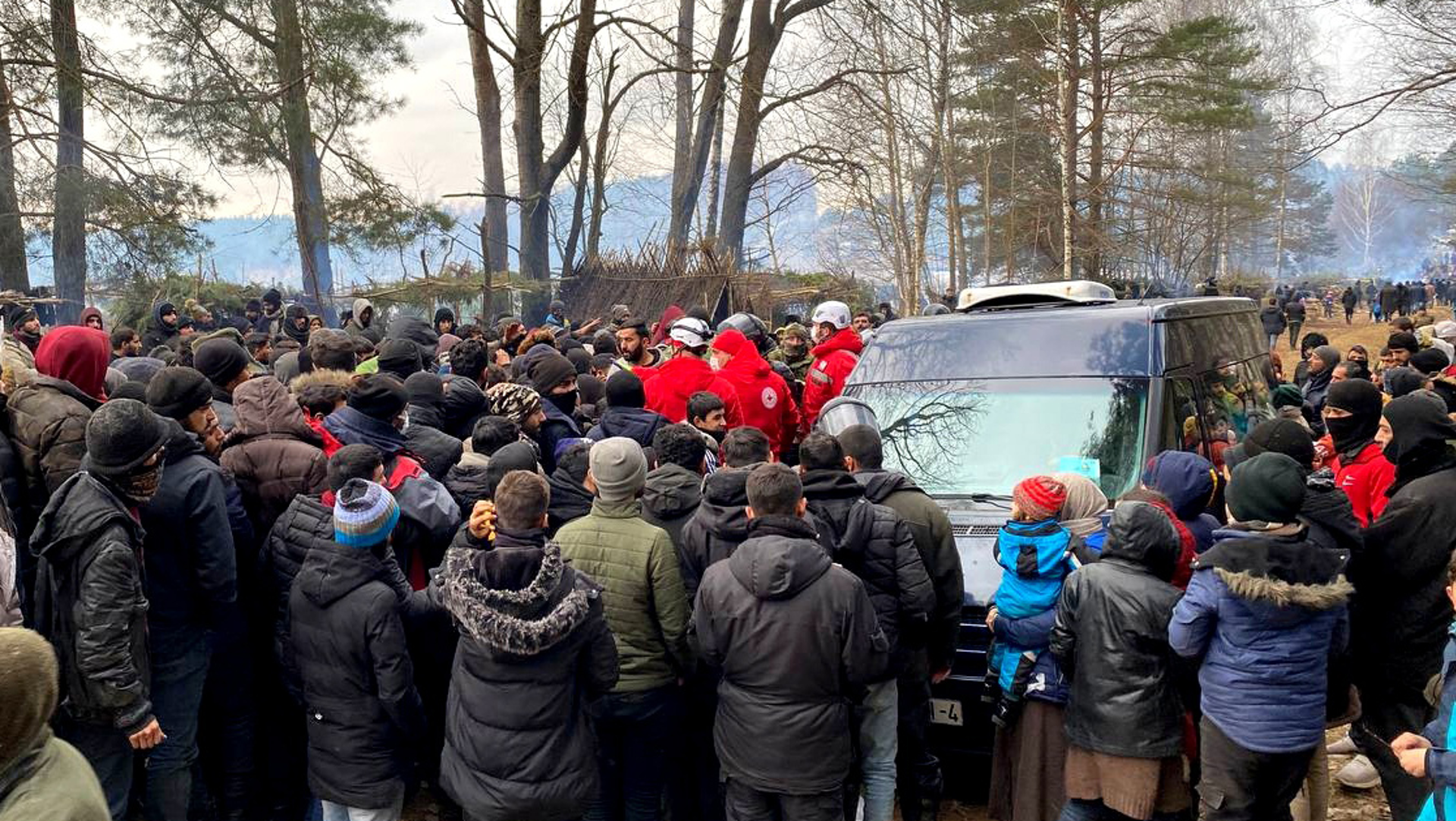 Aid workers from the Belarusian Red Cross standing in a large crowd.