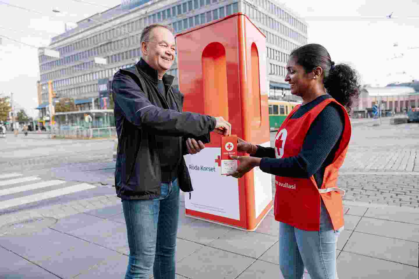 A person puts money in a Hunger Day money box.