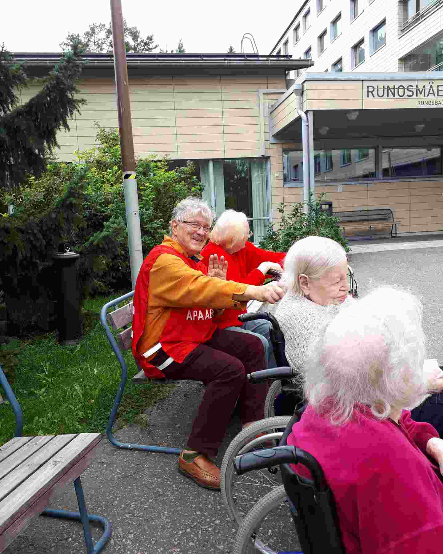 A smiling Red Cross volunteer taking residents of a nursing home outside.