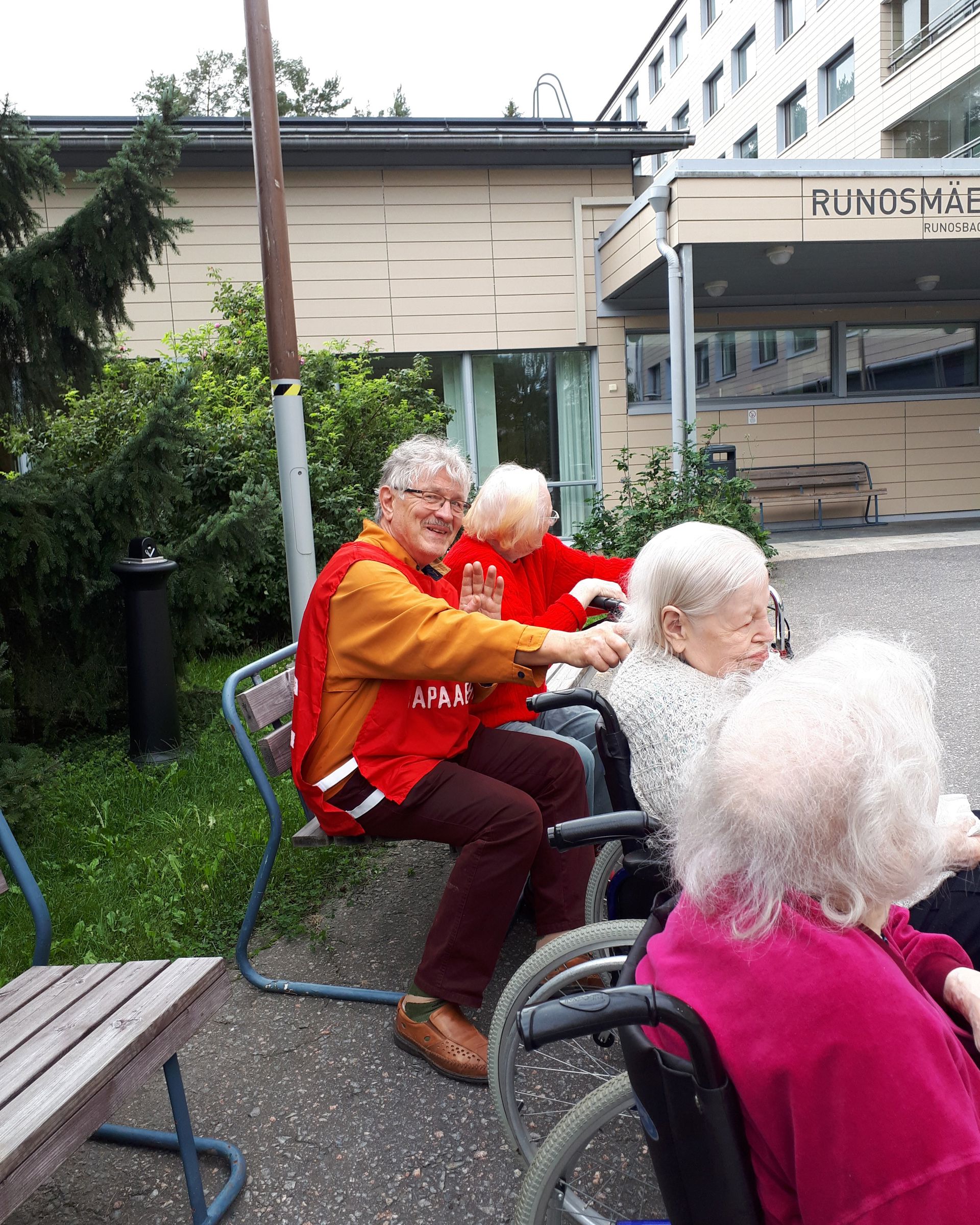 A smiling Red Cross volunteer taking residents of a nursing home outside.