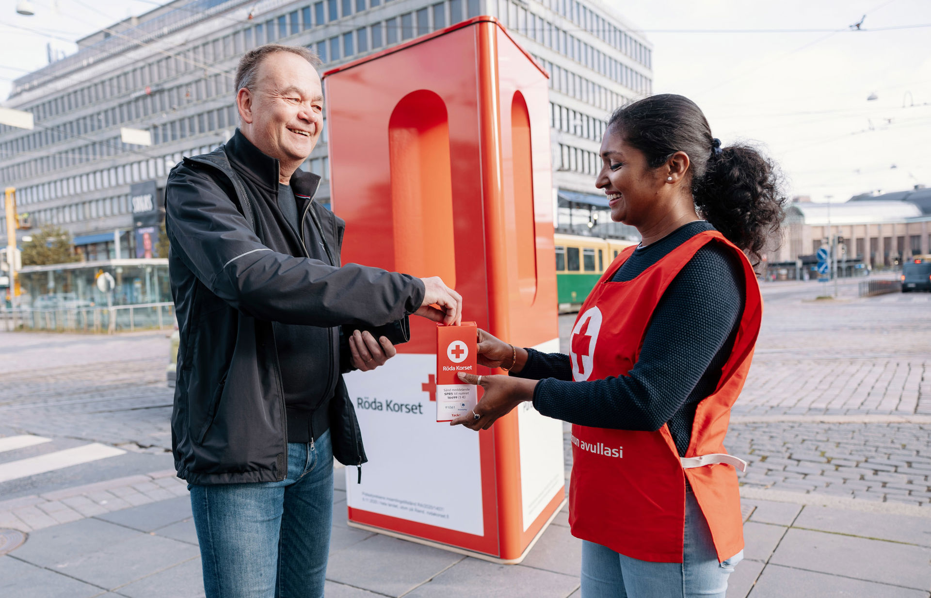 A smiling Hunger Day box collector handing out the box to a smiling donor.