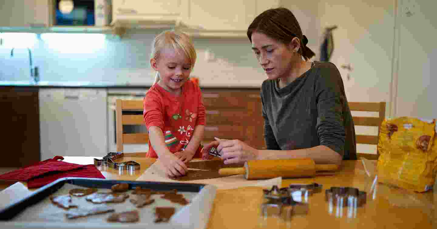 Mother and child baking gingerbread cookies in their home kitchen.