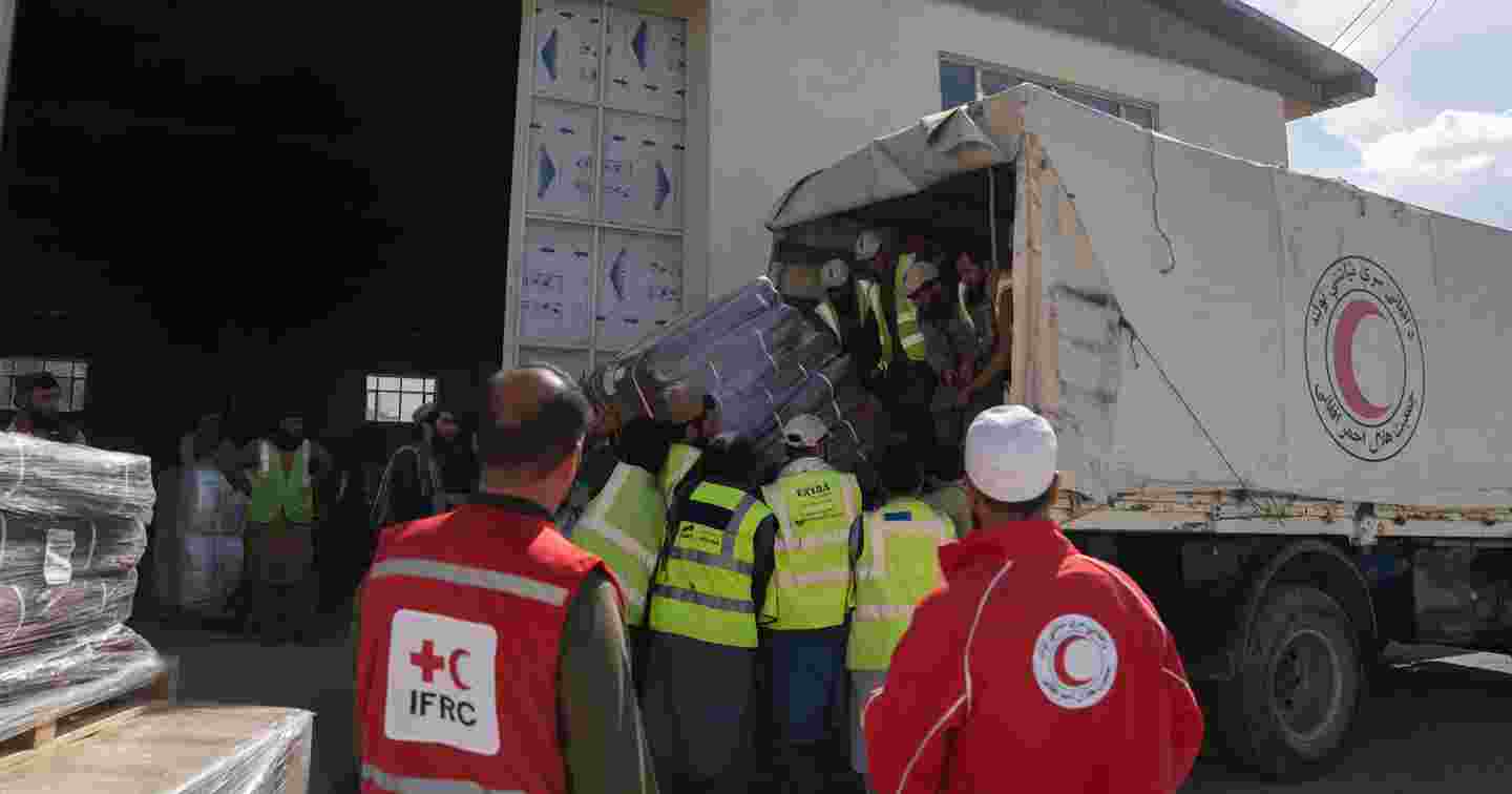 Persons unload aid supplies from an Afghan Red Crescent truck.