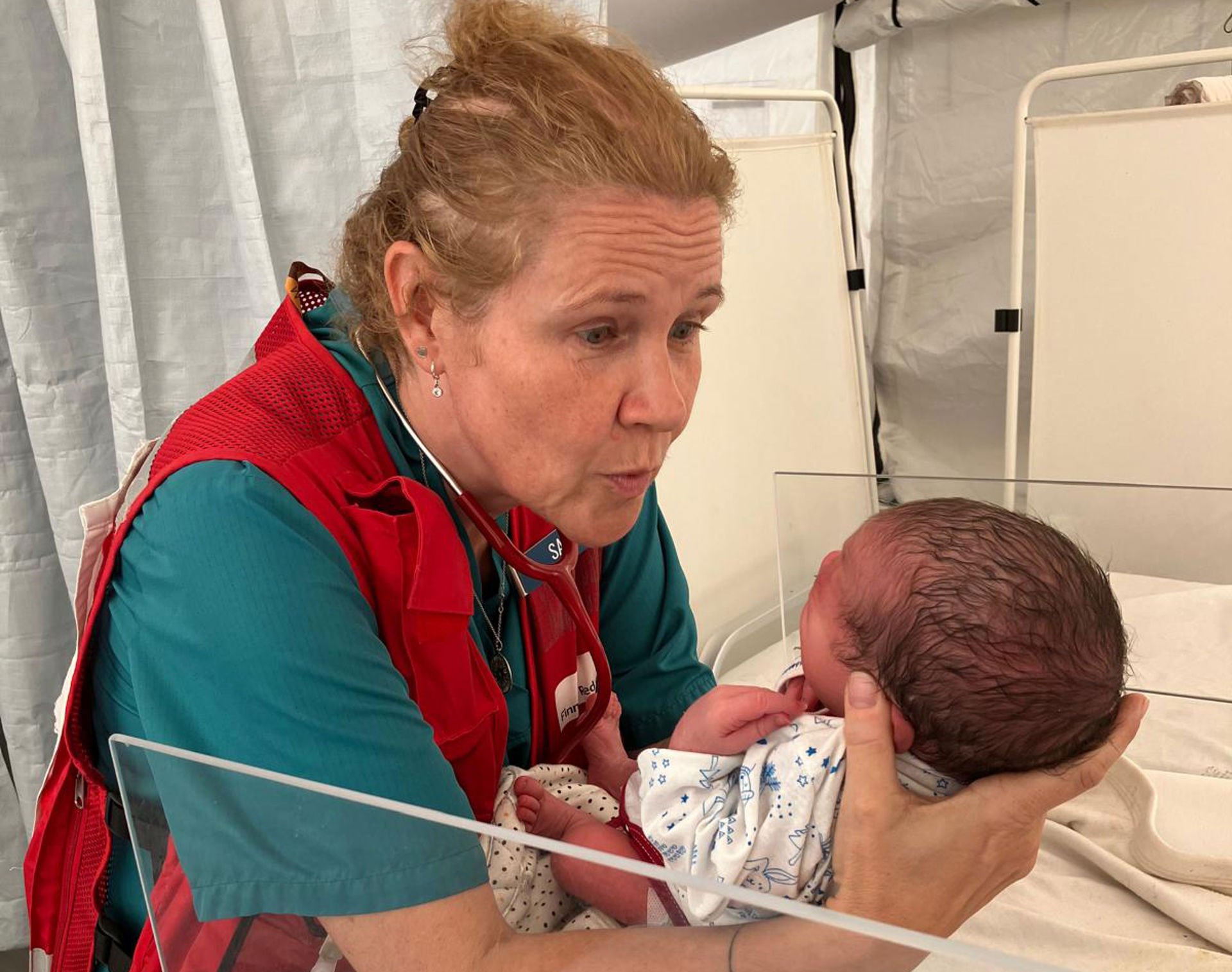 Satu Kekomäki is holding a newborn baby in the Red Cross field hospital in Gaza.