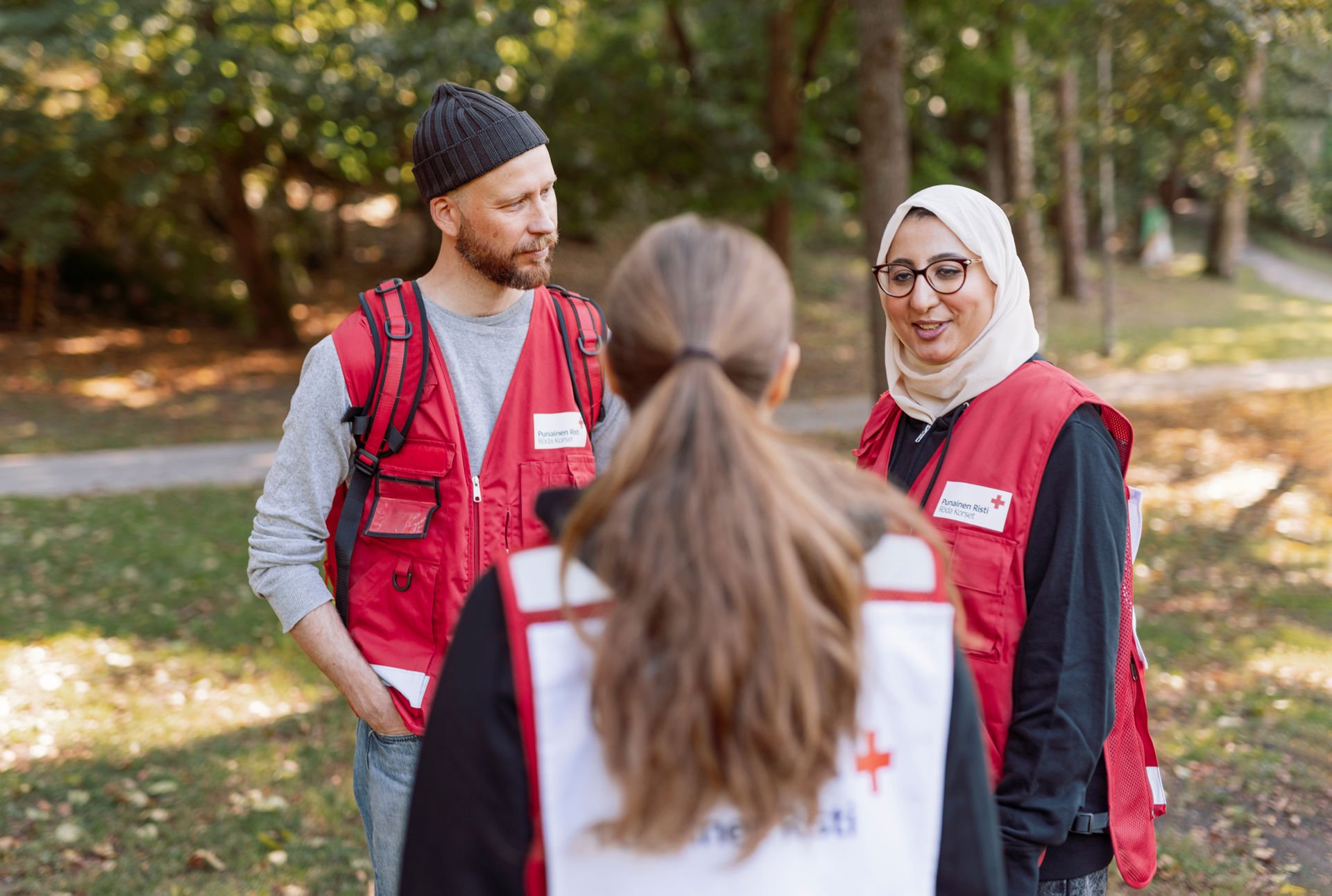 Three Red Cross volunteers are chatting outside in the summer weather.