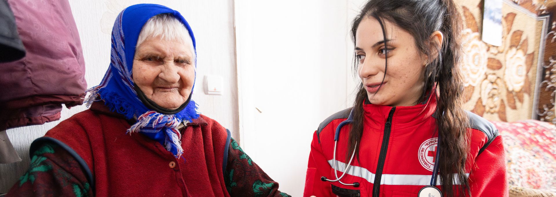 Red Cross aid worker feeding nutrient solution to a newborn baby.