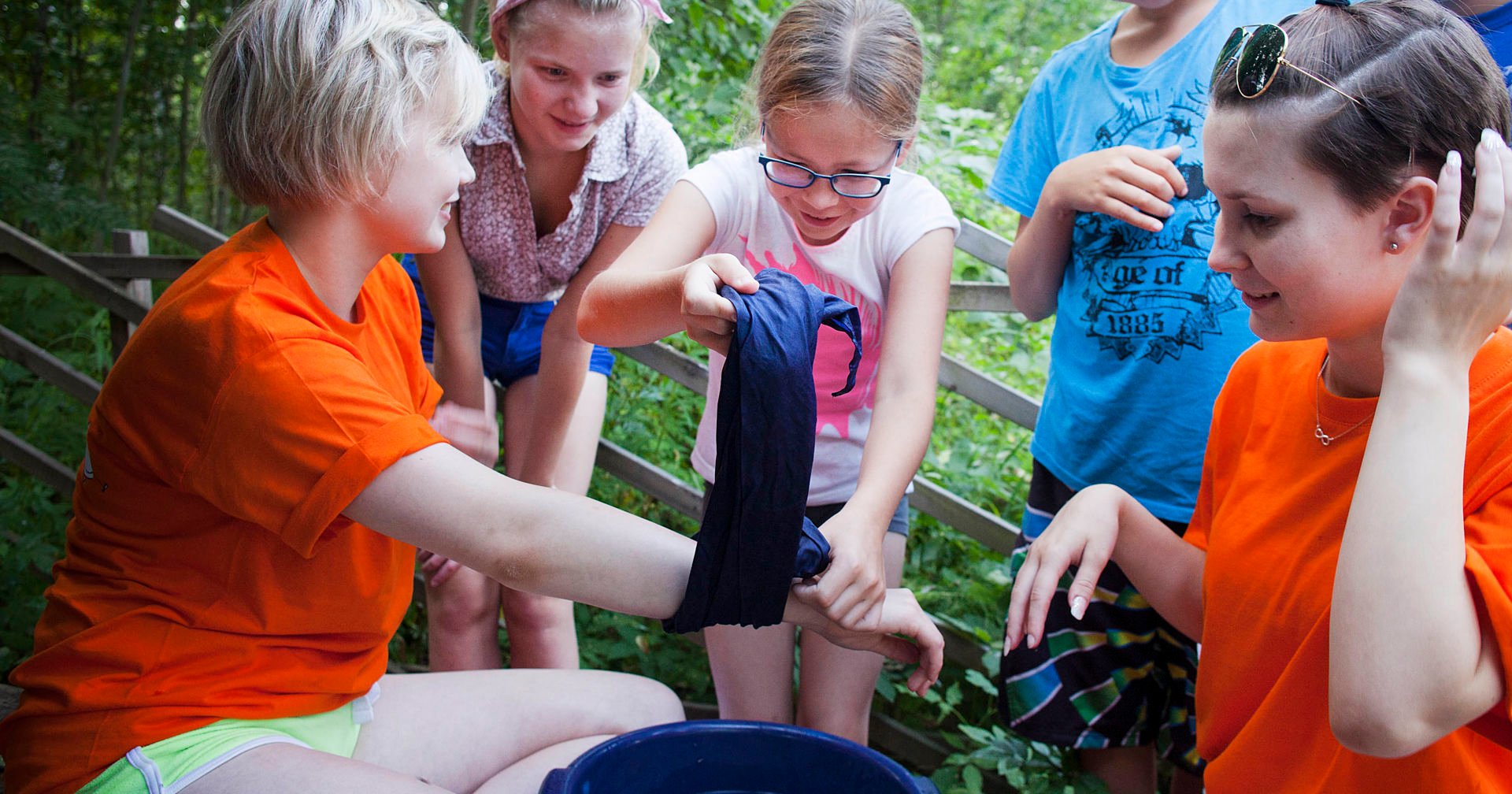 Five children outdoors in summer practicing dressing a wound.