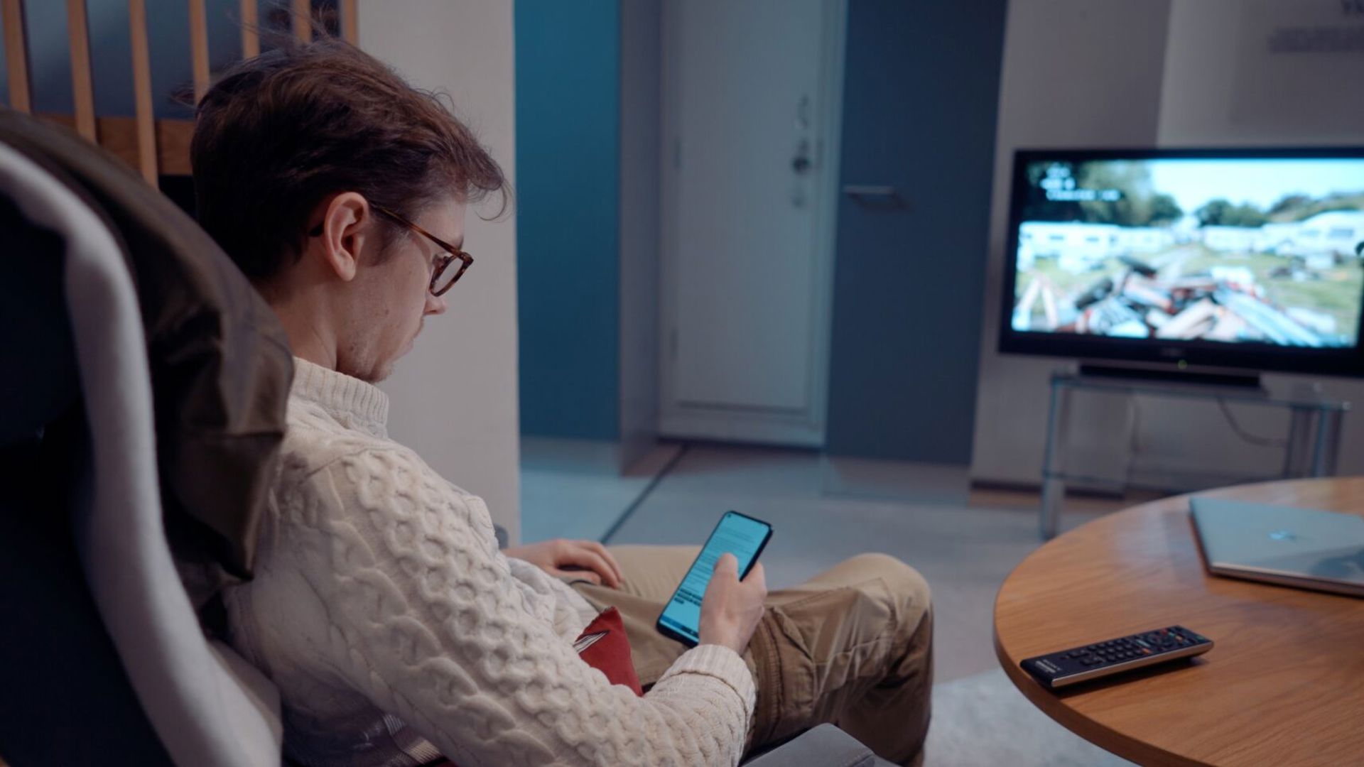 A person is sitting in an armchair with a smartphone in their hand.