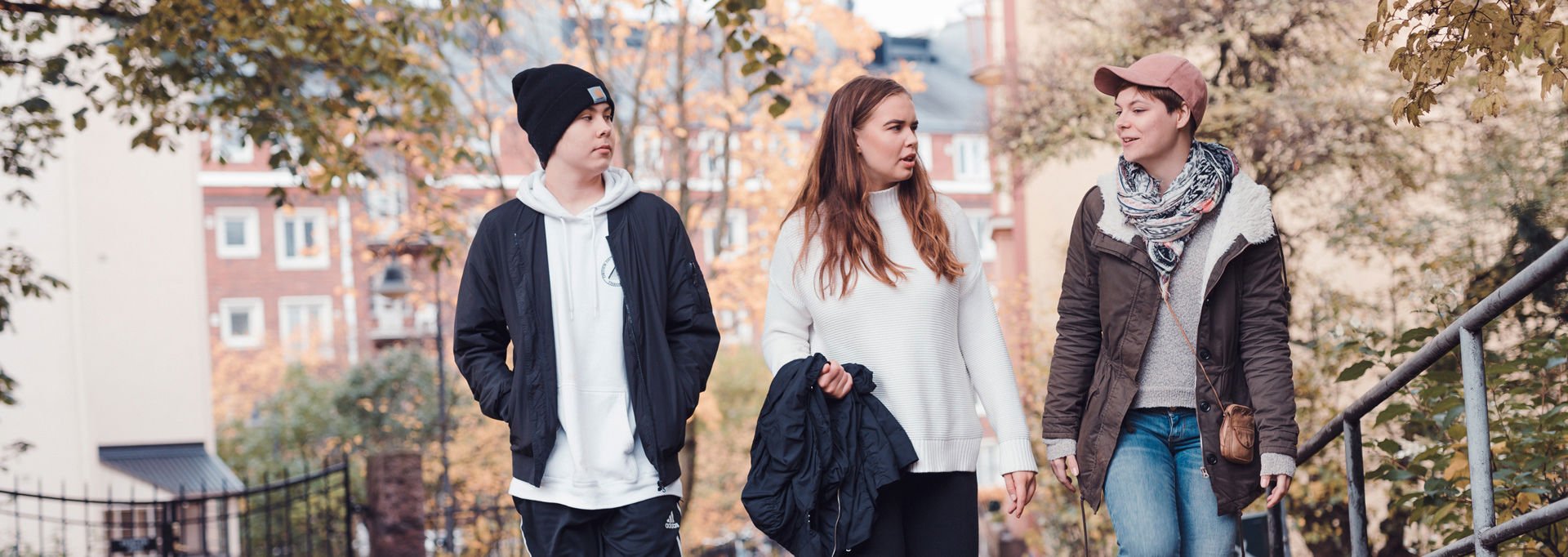 Three young people walking outside in a sunny autumn weather.