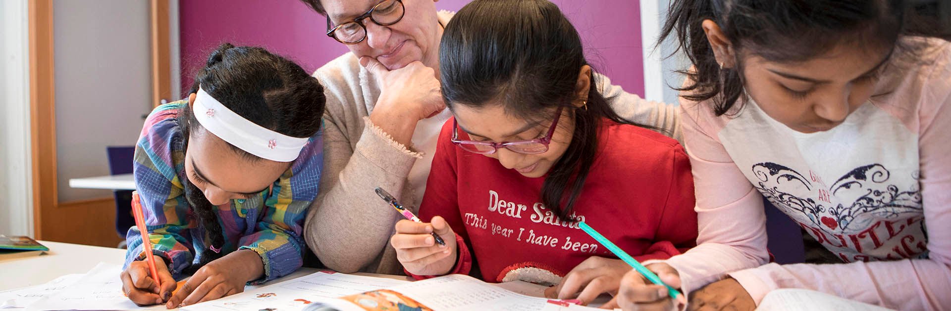 A woman is teaching three young immigrant girls.