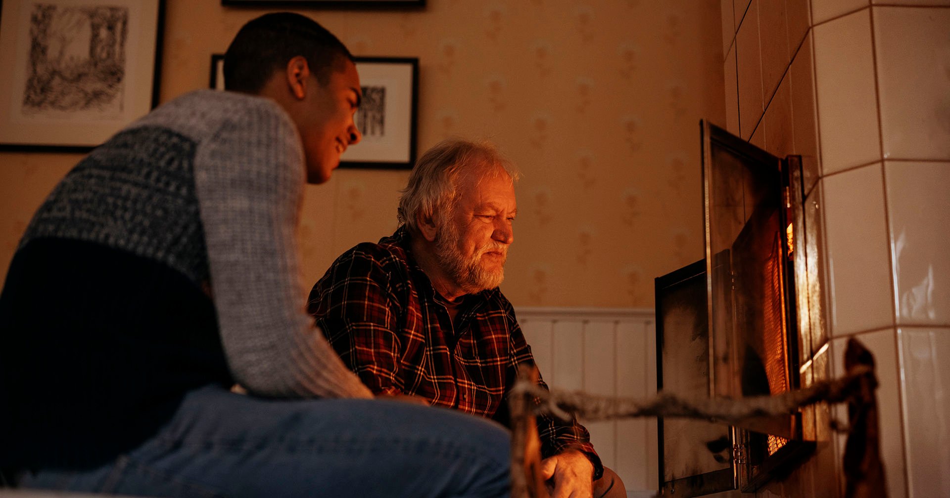 Two elderly people talking and holding a laptop computer and smartphone.