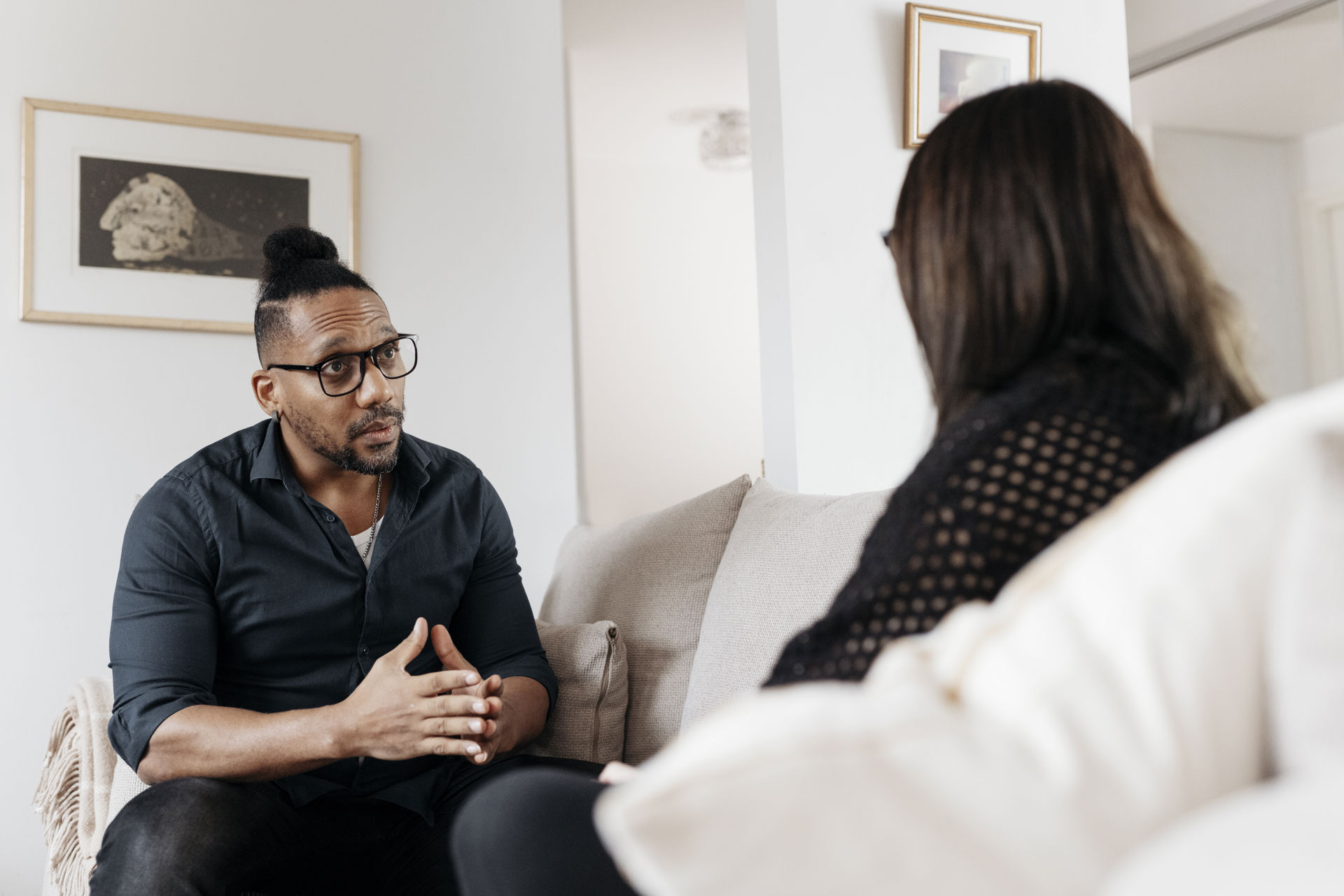 A young person and an adult talking on a couch