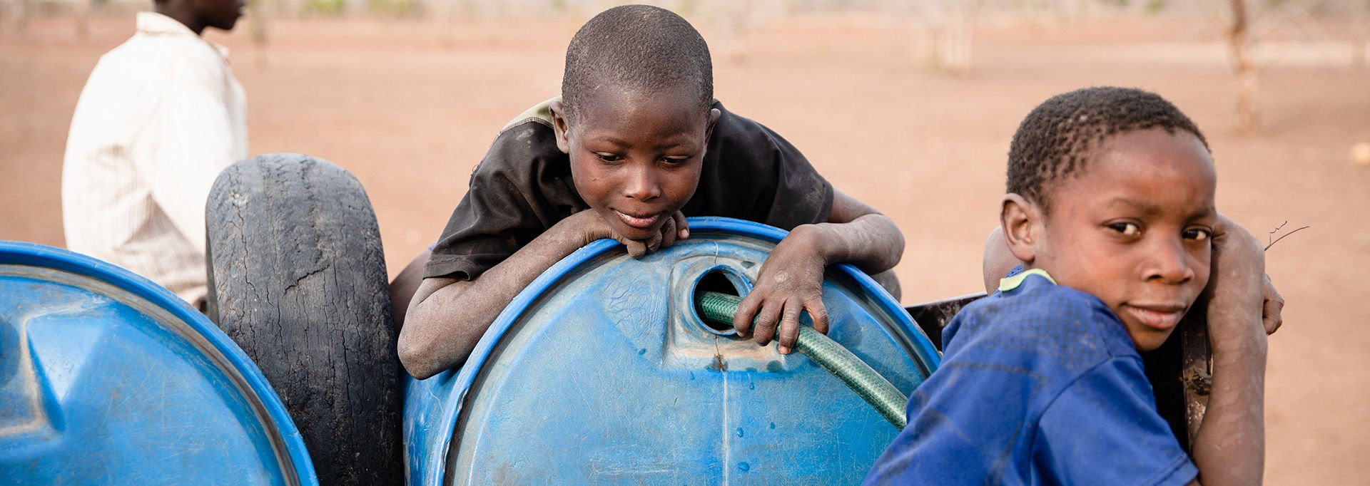 Three Zimbabwean boys by clean water barrels.