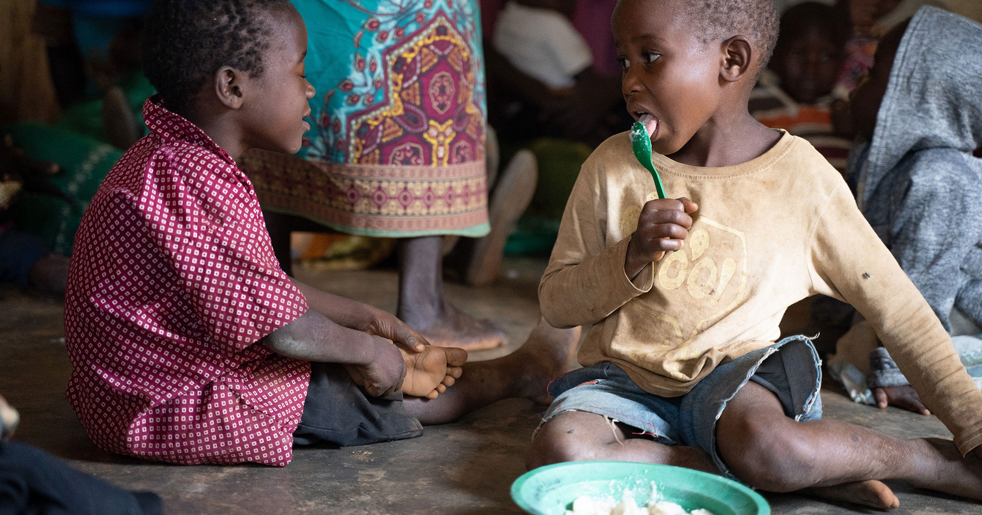 Two children eating porridge in daycare.