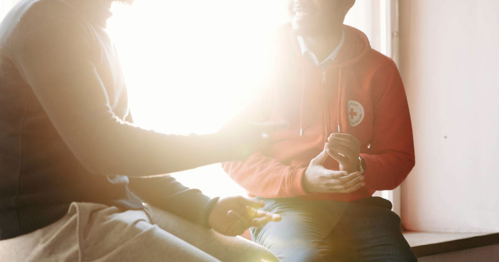 Two men talking in front of window