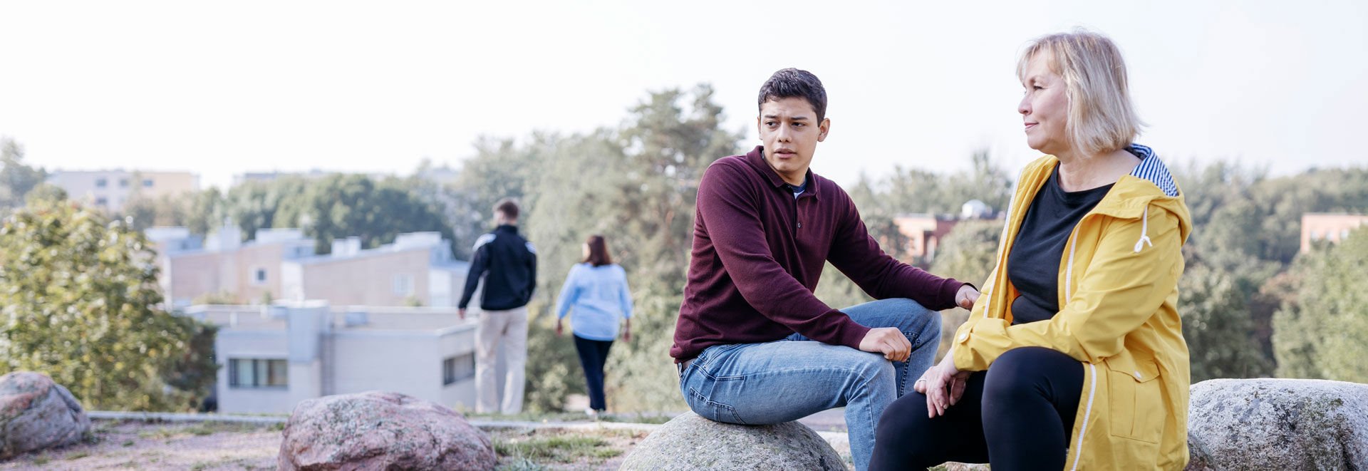 A young person and an older person talking outdoors in an esker landscape.