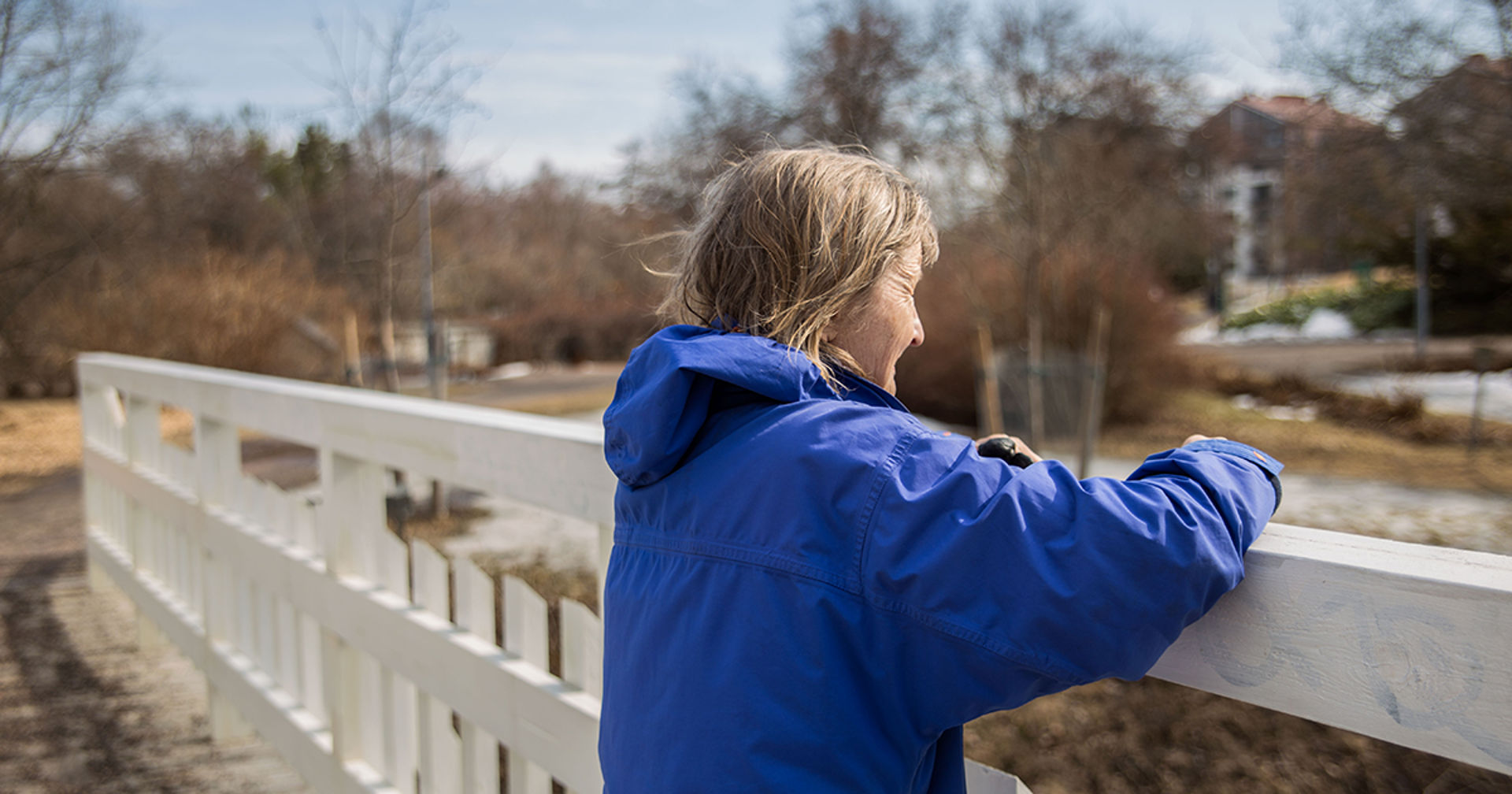 A person leaning on a bridge and looking ahead.