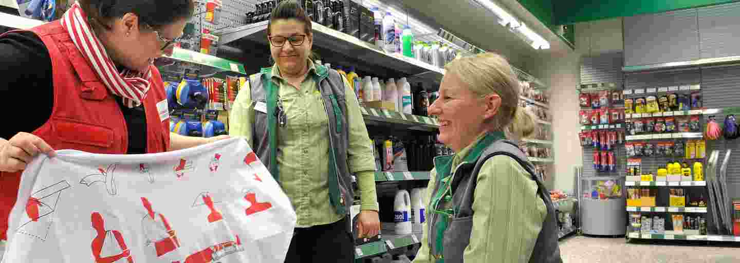 A woman wearing Red Cross gear teaching first aid to shop employees.
