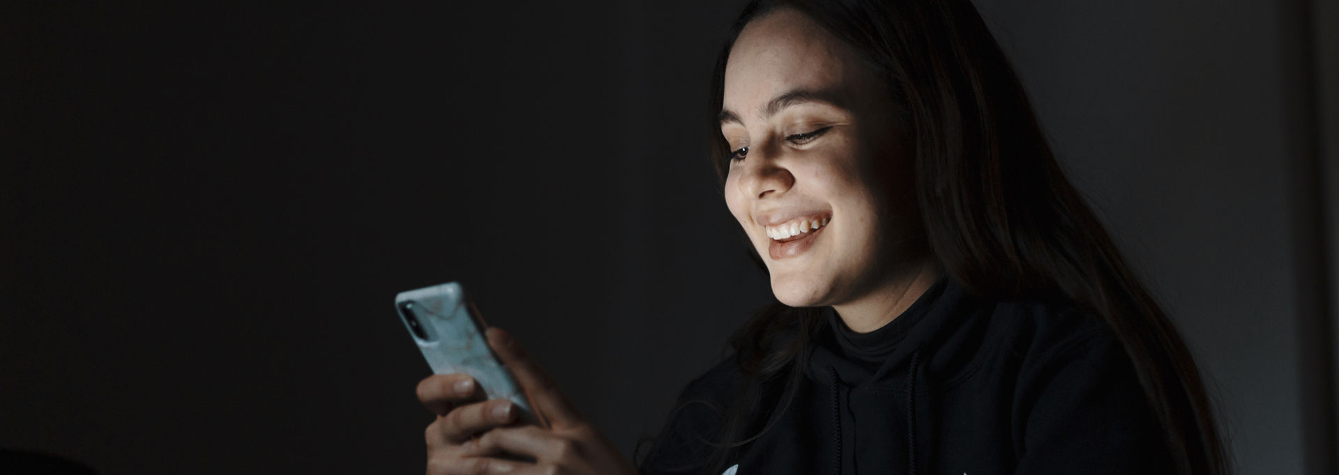 Girl looks at her phone with smile on her face